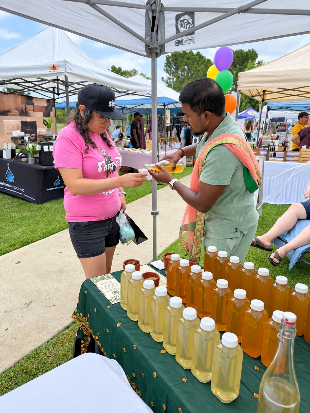 Sharing Satvik herbal water samples at an outdoor farmers market