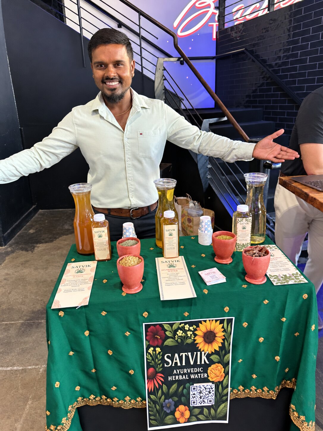 Satvik founder welcoming guests at an indoor community event table